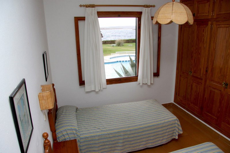 Dormitorio con camas individuales y ventana que da a la piscina comunitaria.