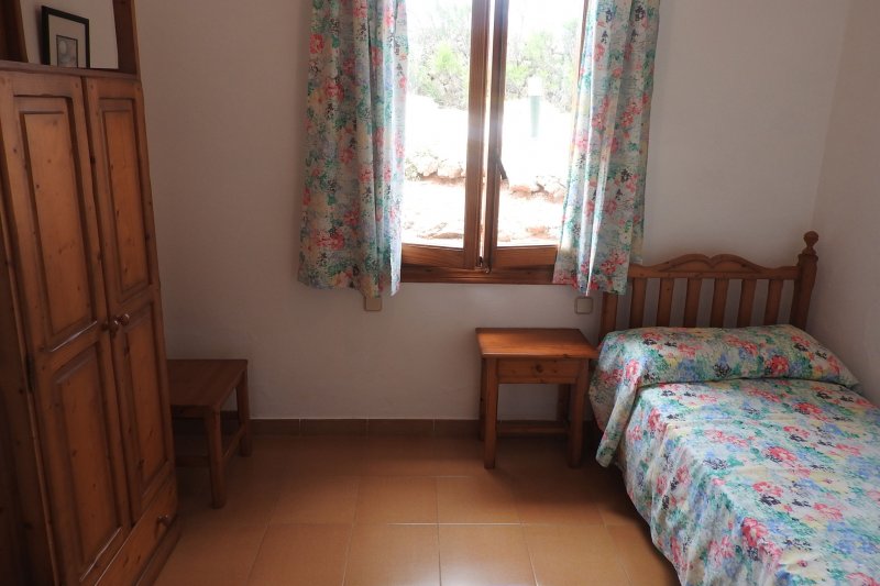 Dormitorio con cama individual y ventana que da al recinto de Rocas Marinas.