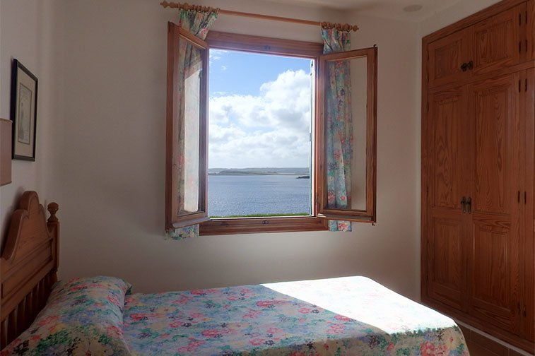 Ventana del dormitorio con camas individuales que da al la costa de Menorca.