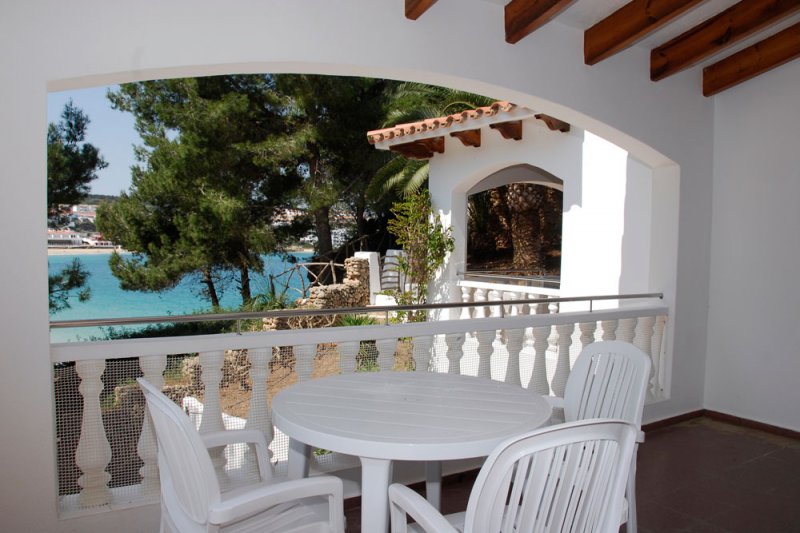 Vista de la terrassa coberta dels apartaments Jardín Playa 1, cap a una platja de Menorca.