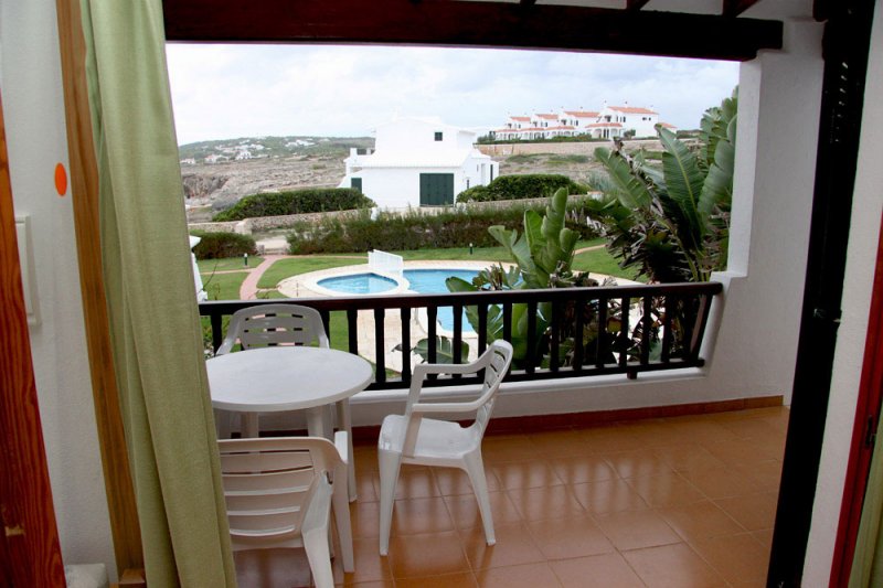 Covered terrace and balcony facing the pool and the grounds of the Rocas Marinas Apartments.