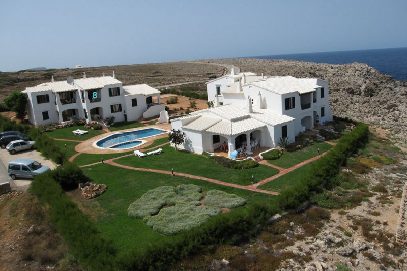 El complejo de apartamentos Rocas Marinas desde arriba y con la costa de Menorca de fondo.