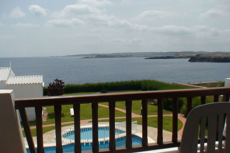 Vista desde la terraza del apartamento Rocas Marinas 8A , a la piscina y la costa de Menorca.