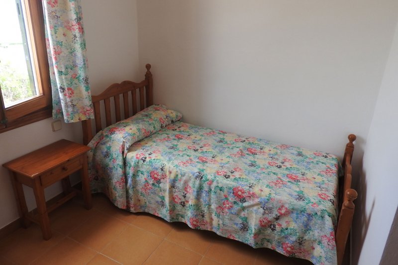 Dormitorio con cama individual y ventana que da al recinto de los apartamentos Rocas Marinas 8R.