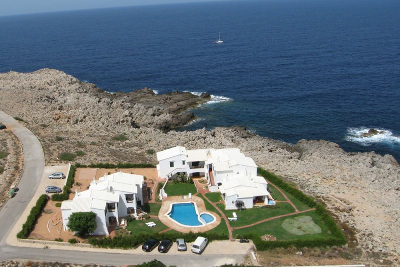 Vista de los apartamentos Rocas Marinas desde arriba y con la costa de Menorca, de fondo.