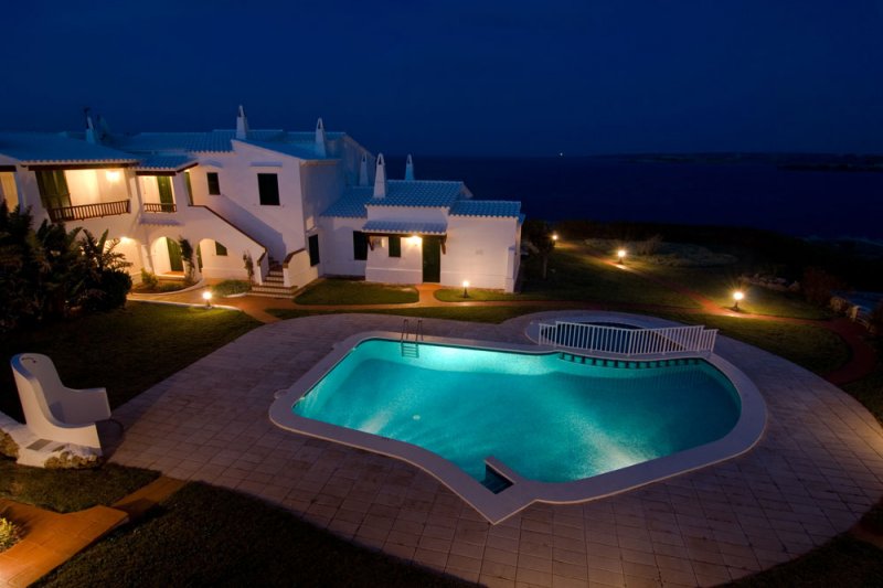 Vista superior de la piscina comunitària dels apartaments Rocas Marinas i la costa de Menorca.
